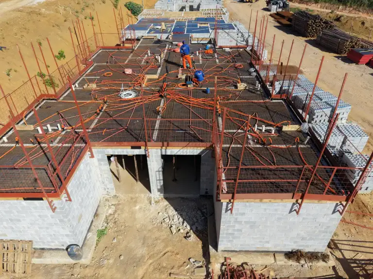 Vista aérea de conjunto de casas geminadas em construção, estrutura metálica e alvenaria.