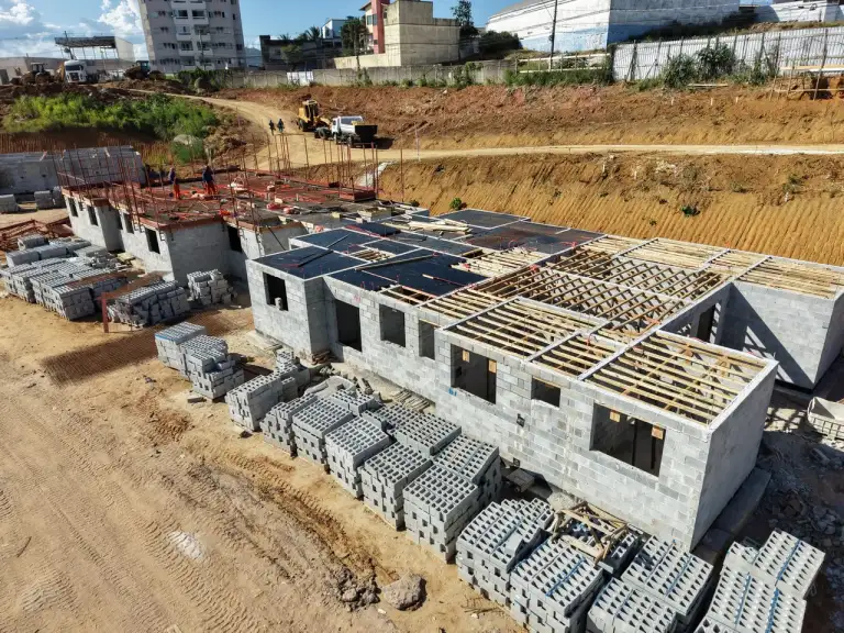 Vista aérea de conjunto habitacional em construção, área urbana ao fundo.