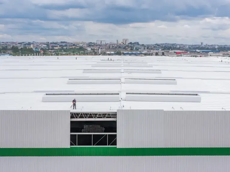 Vista aérea da fachada de galpão industrial concluída, com faixa verde no revestimento metálico.