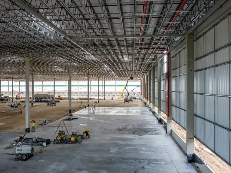 Fachada de vidro recém-instalada em galpão industrial, piso de concreto e estrutura metálica ao fundo.
