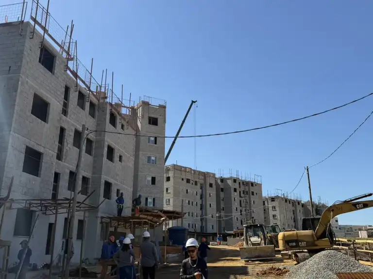 Caminhões betoneira posicionados ao lado de estrutura metálica de edificação em construção.