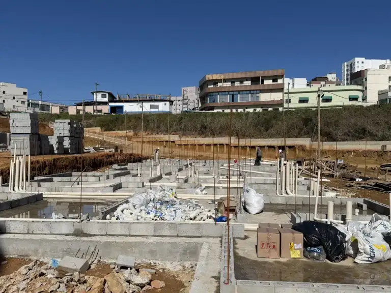 Edifício residencial em construção em área urbana, com caminhão bomba de concreto posicionado na rua.