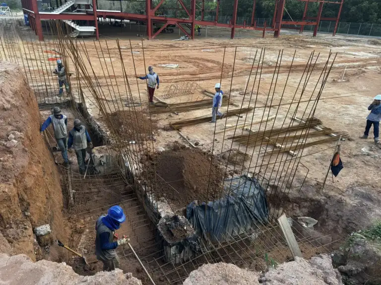 Fachada de edificação residencial em construção, cercamento de obra em primeiro plano.