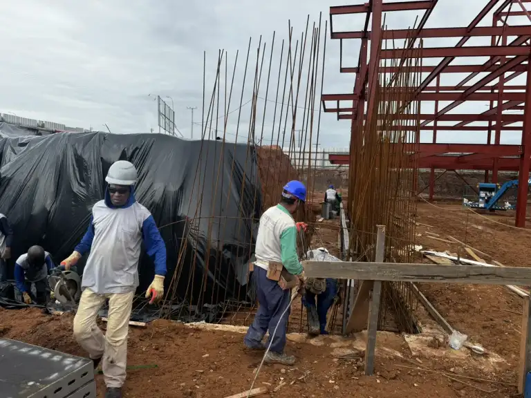 Fundação em ferragem sendo preparada por equipe de profissionais em canteiro de obras.