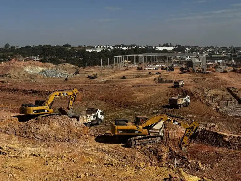 Escavadeiras realizando terraplenagem em terreno amplo para início de obra.
