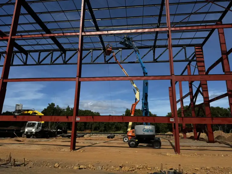 Estrutura metálica de edificação em construção sob céu com nuvens.