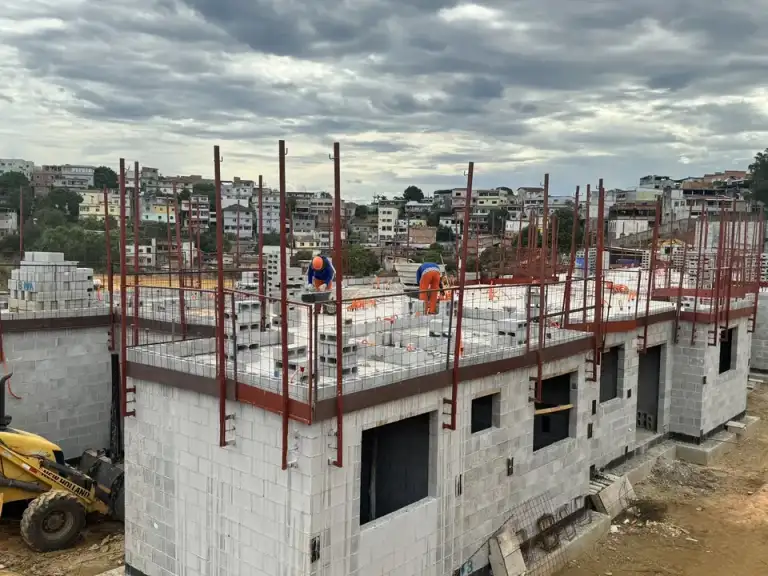 Casas geminadas em construção em alvenaria, estrutura metálica em primeiro plano.