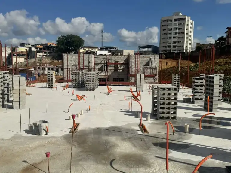 Conjunto de casas em construção com lajes de concreto, área urbana ao fundo.