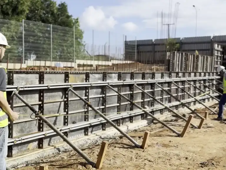 Montagem de estrutura metálica de edificação em construção, filmagem em nível de solo.